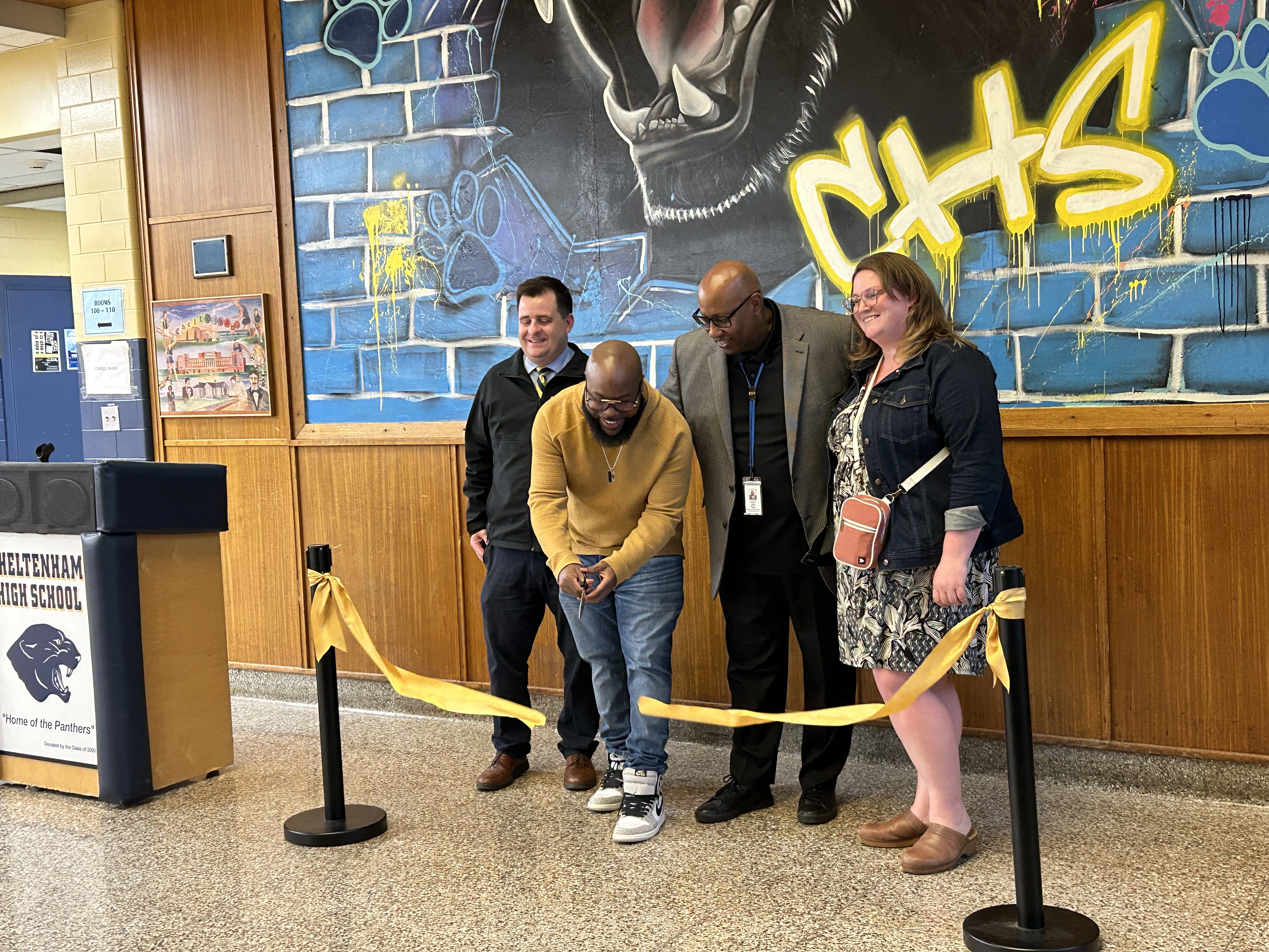 Amir Campbell cutting the ribbon to his mural.