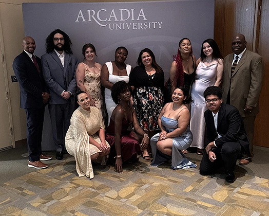 Leadership for the H.O.M.E. program stand in front of an Arcadia University grey backdrop.