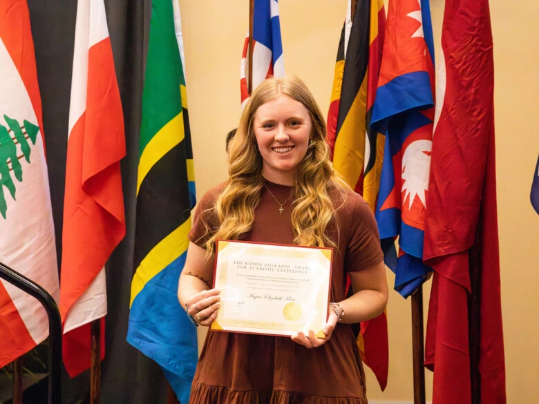 Megan Elizabeth Klose holds a framed keepsake f the Kusum Kulkarni Award for Academic Excellence, formerly known as The Excellence in Communications Award.
