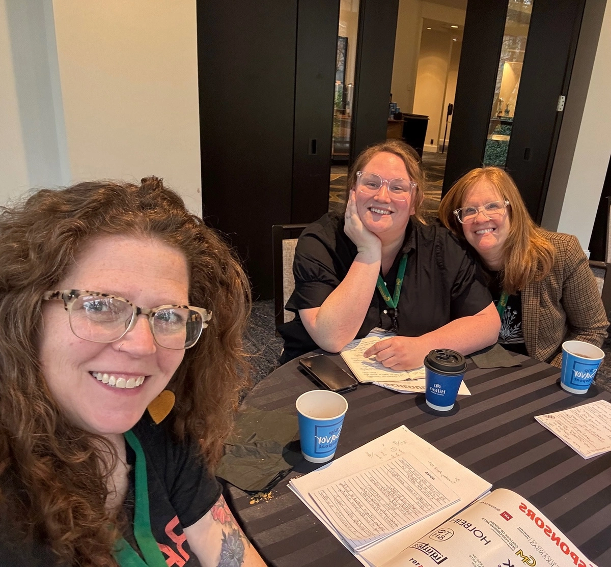 Profs. Carole Loeffler, Krista Profitt ’11, and Maryann Worrell ’05 sitting at a table after their conference session
